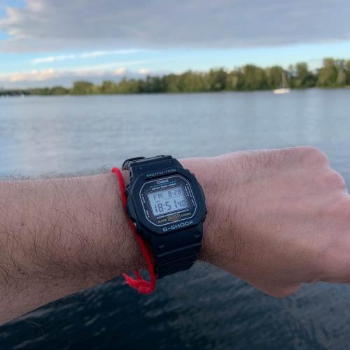 Фото противоударных наручных часов CASIO G-SHOCK DW-5600E-1VER на мужской руке на фоне Днепра.