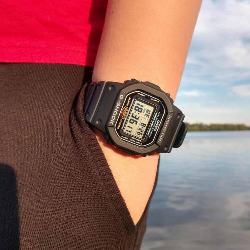 Фото водонепроницаемых наручных часов CASIO G-SHOCK DW-5600E-1VER на запястье ребенка на пляже.