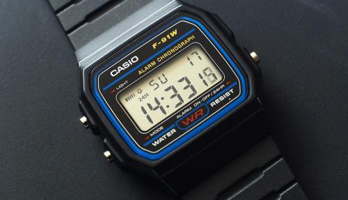 Монохромный дисплей электронных часов CASIO F-91W-1YEF защищен акриловым стеклом с рамкой черно-синего цвета.