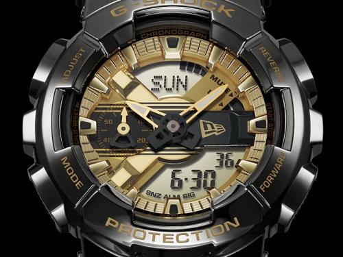Черно-золотой циферблат часов CASIO G-SHOCK GM-110NE-1AER украшен логотипом компании New Era Cap Company.