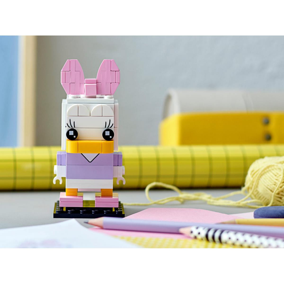 Персонаж Дейзи Дак из набора LEGO® BrickHeadz™ Disney Daisy Duck (40476) с розовым бантиком и V-образным печатным принтом.